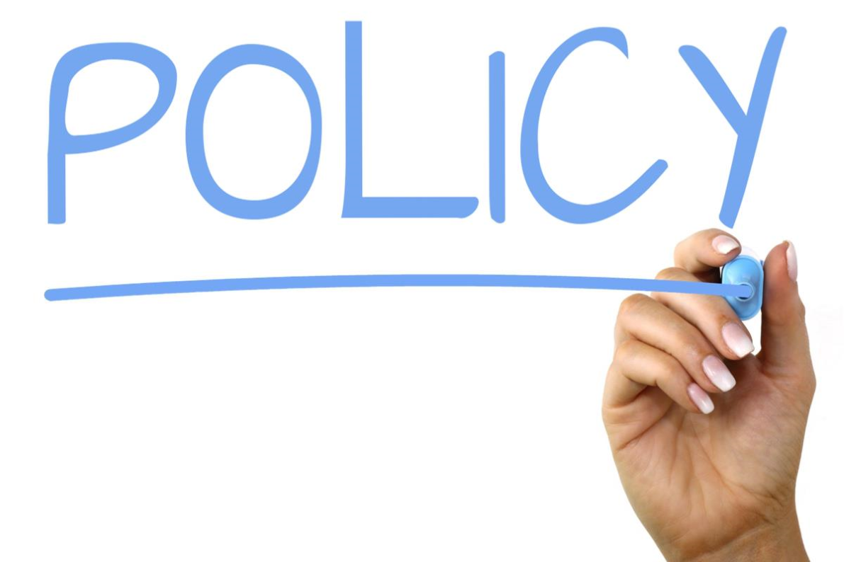 Hand som skriver Policy med blå penna